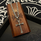 Silver-tone cross pendant necklace displayed on wooden box