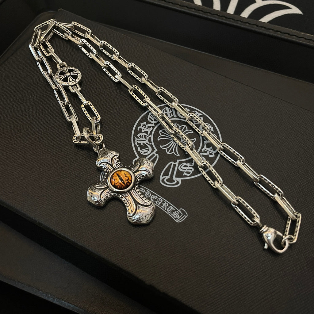 Silver-tone chain necklace with amber cross pendant on black tray