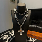 Silver-tone chain necklace with amber cross pendant and round charm on stand