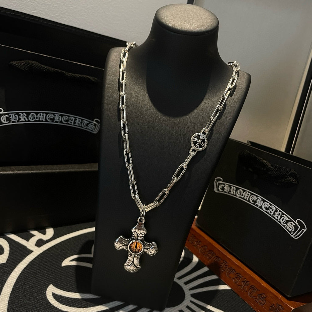 Silver-tone chain necklace with amber cross pendant on display stand, side view