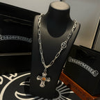 Silver-tone chain necklace with amber cross pendant on display stand, side view