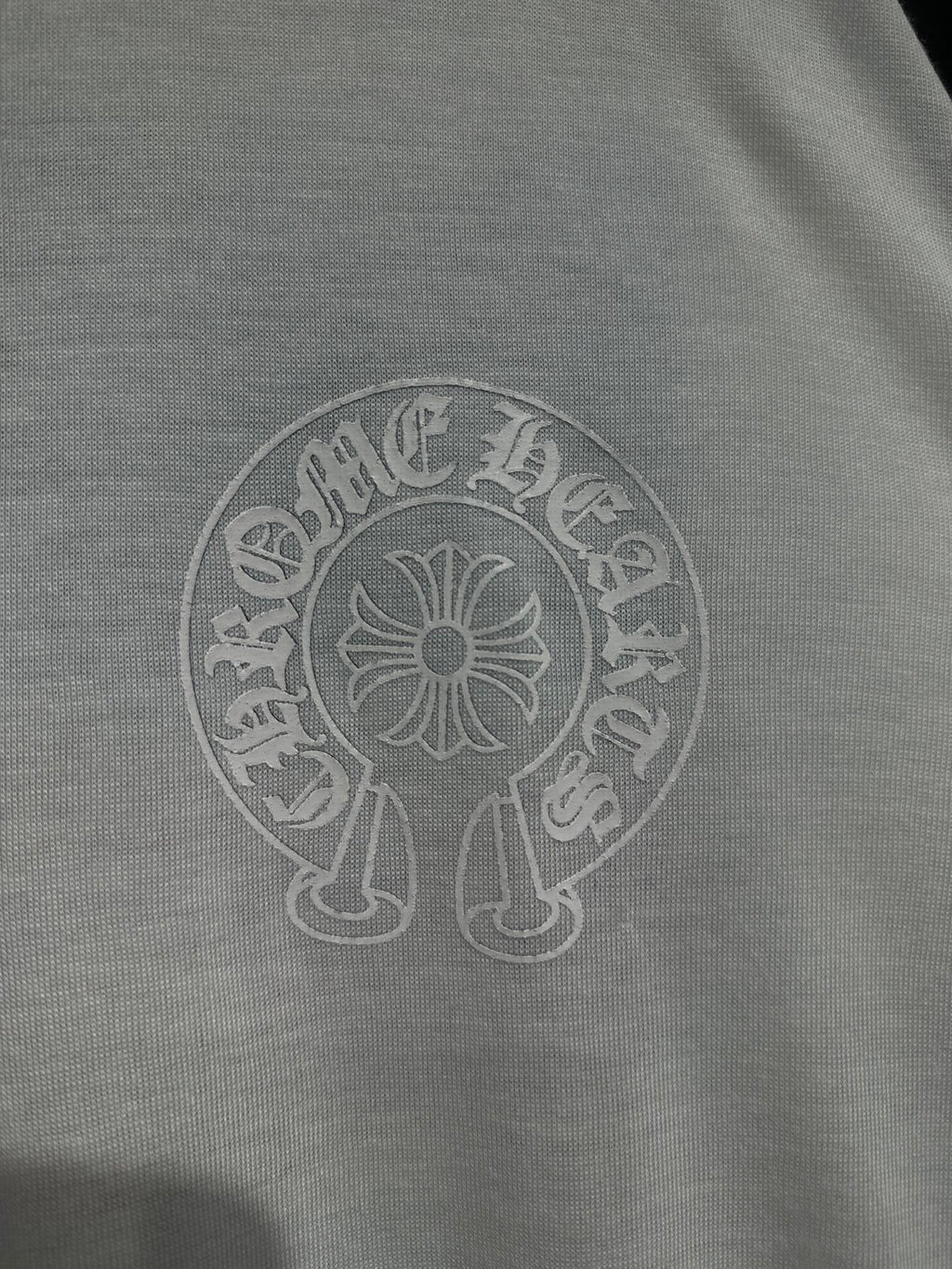 White long-sleeve shirt close-up of circular crest logo print on chest.