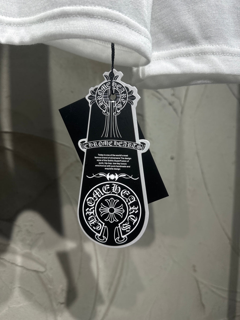 White long-sleeve shirt hanging with black tag and white emblem graphic.