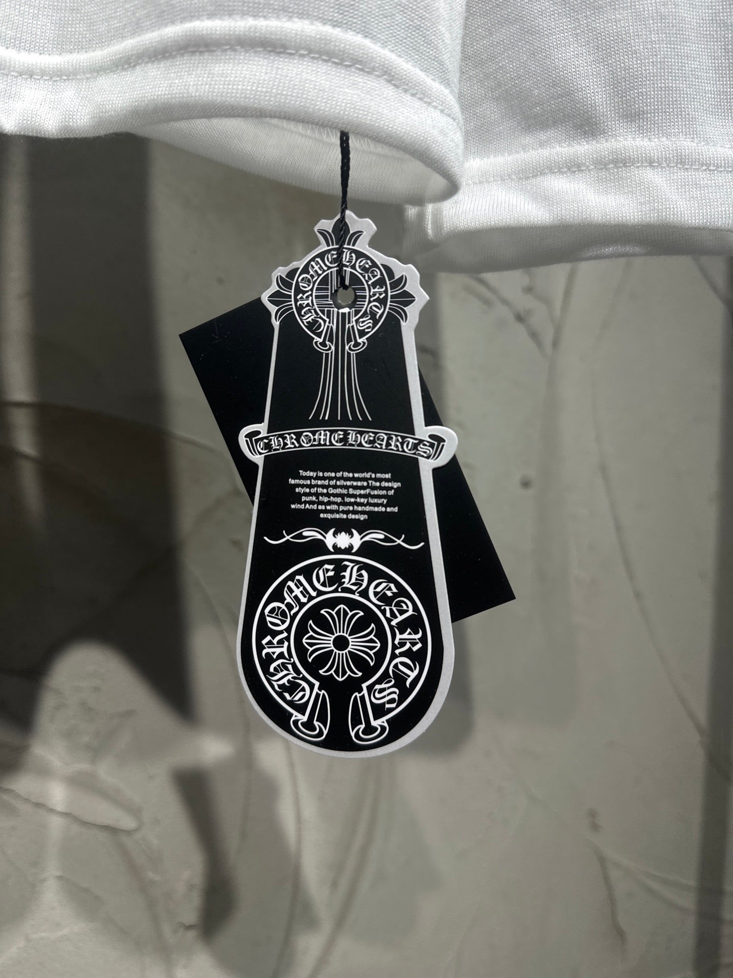 White long-sleeve shirt hanging with black tag and white emblem graphic.