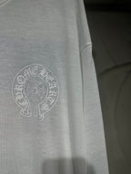 White long-sleeve shirt side close-up with circular crest logo print.