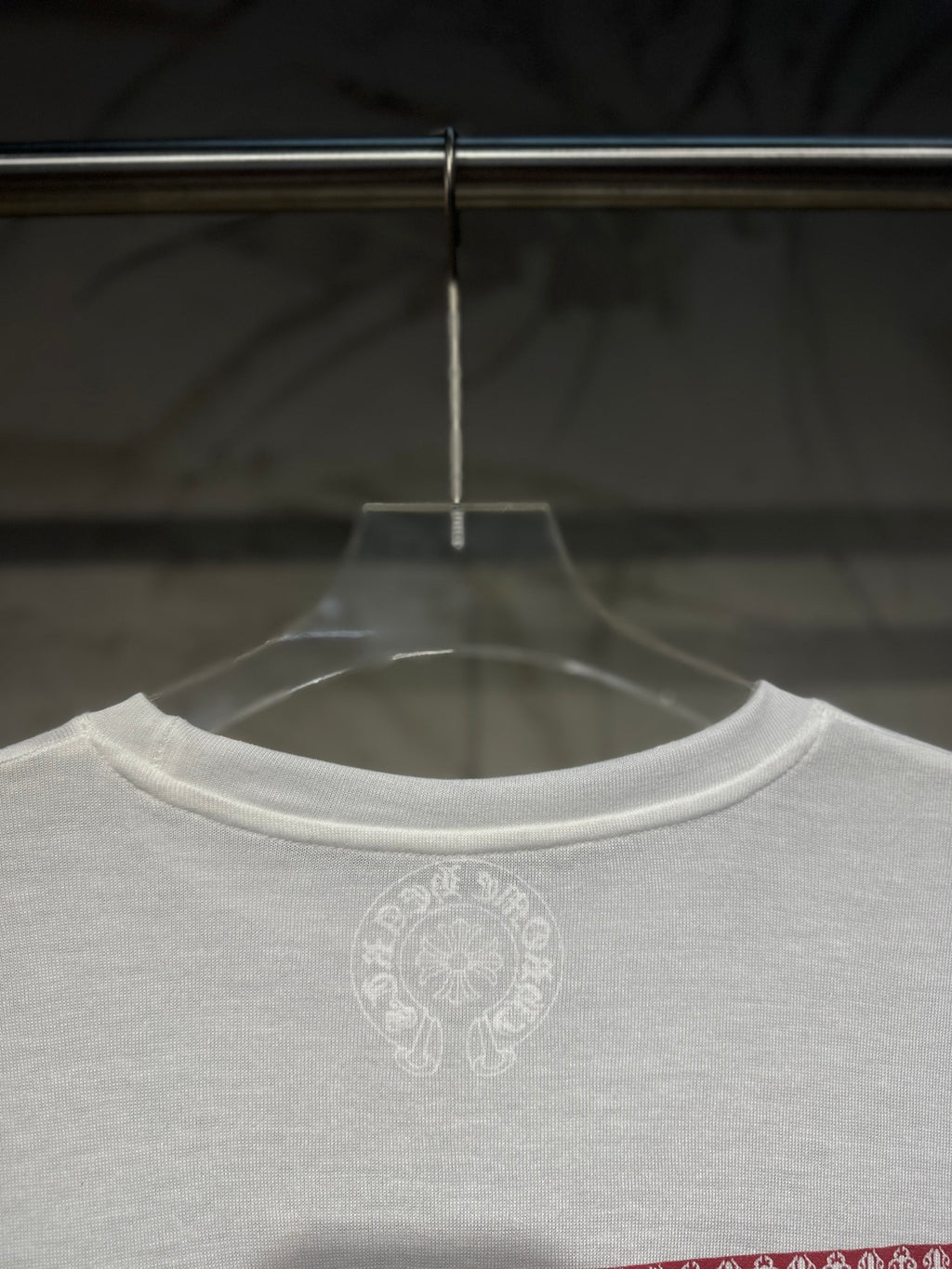 White long-sleeve shirt front neckline with small circular chest logo.