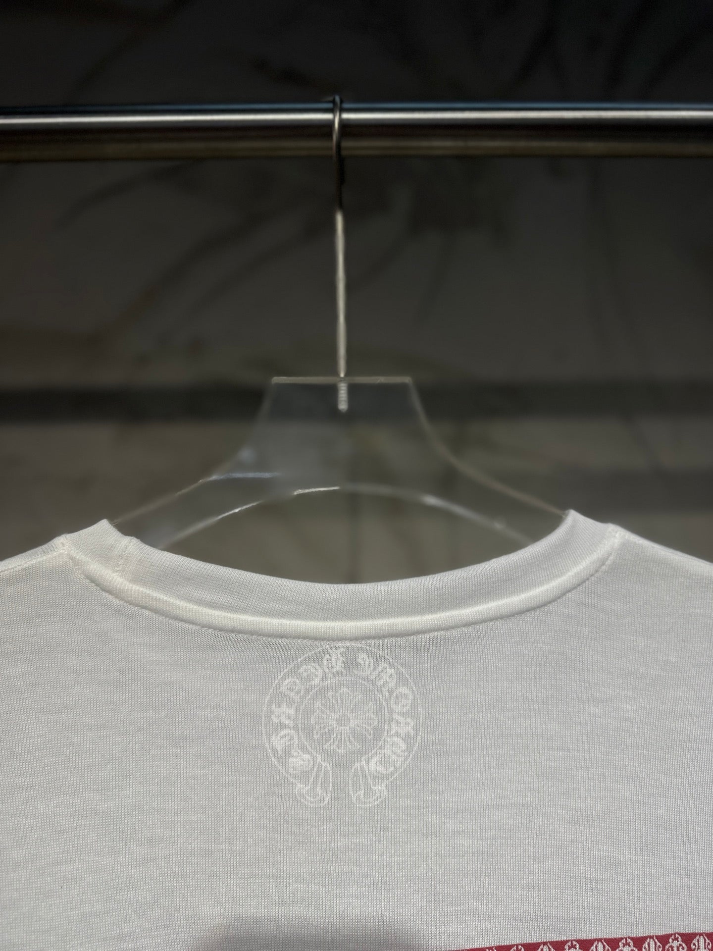 White long-sleeve shirt front neckline with small circular chest logo.