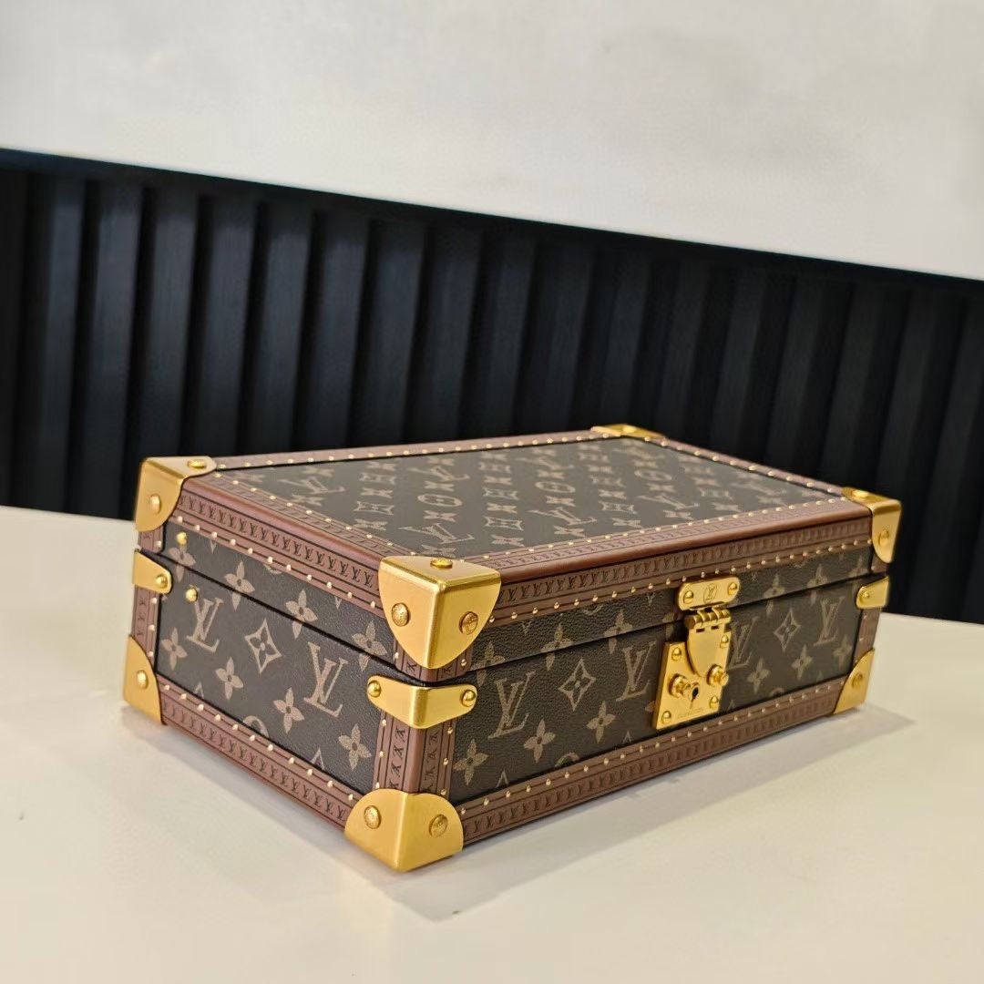 Louis Vuitton monogram trunk bag with gold corner hardware and brown trim, angled view