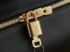 Louis Vuitton zipper pull close-up with gold hardware on black textured leather.