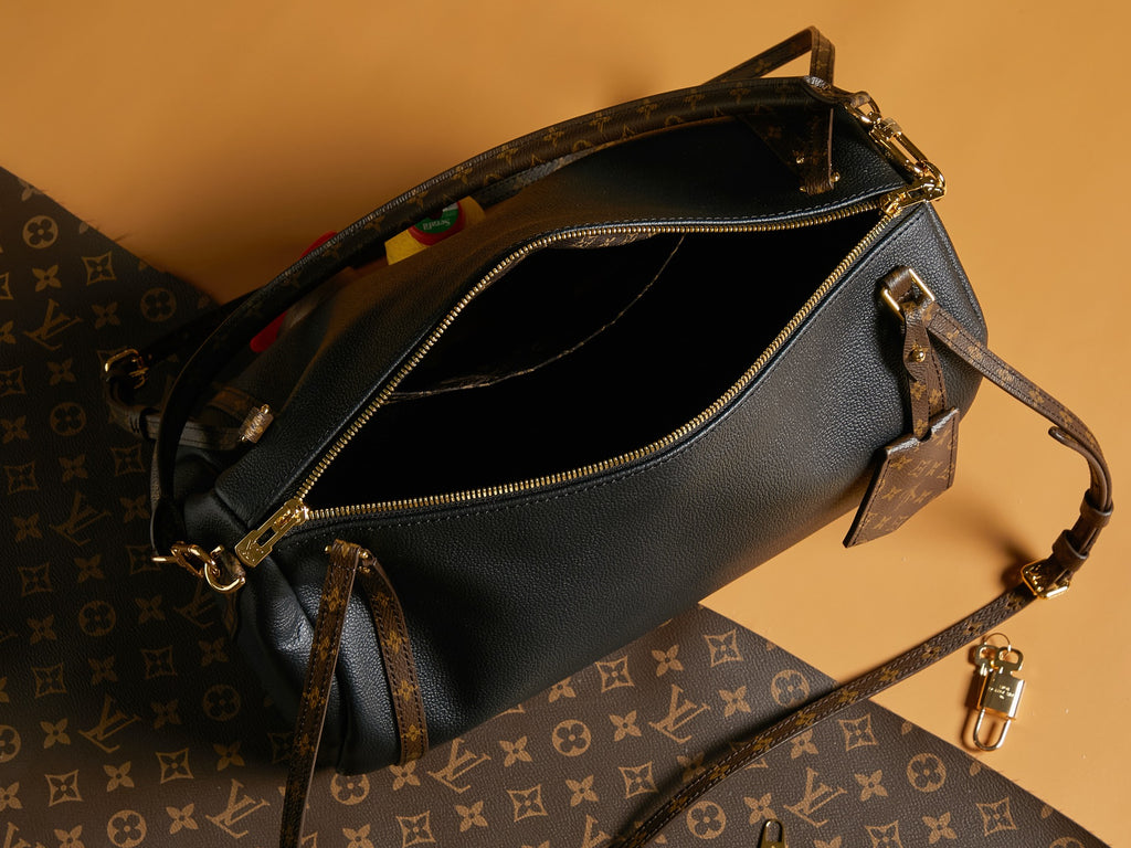 Louis Vuitton black leather bag interior view with zip pocket and adjustable strap.