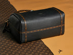 Louis Vuitton black leather duffel-style bag with tan trim and top handles.