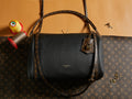 Louis Vuitton black leather handbag with top handles, strap, and front flap.