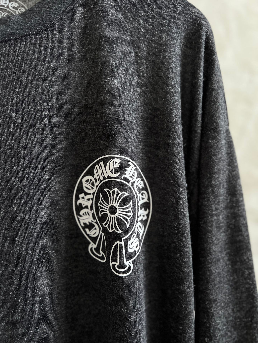 Close-up of circular crest logo on dark heather gray long-sleeve T-shirt