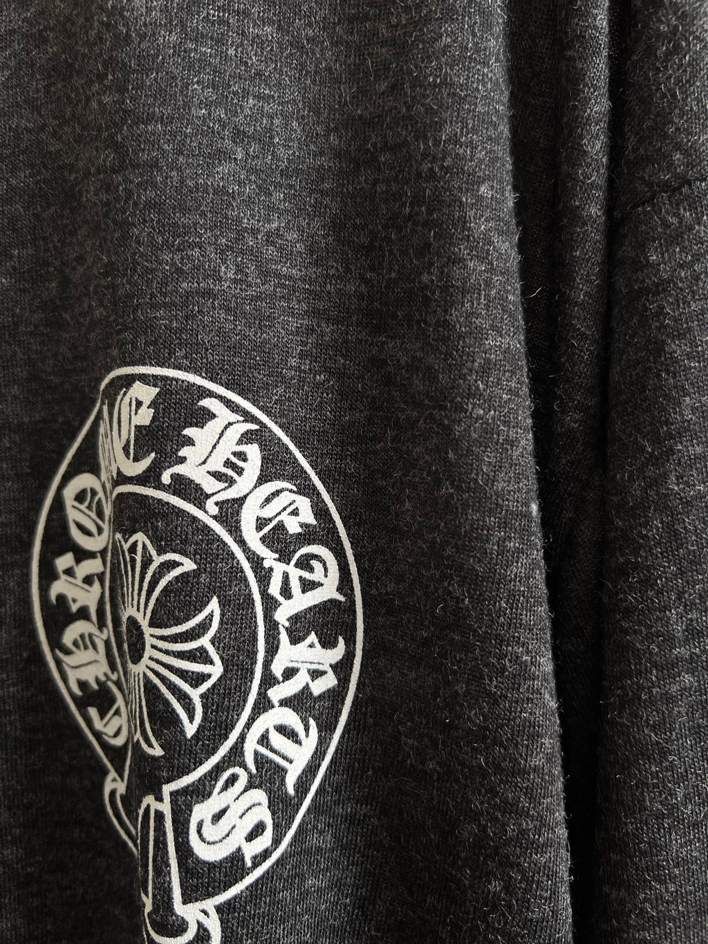 Close-up of circular crest logo on dark heather gray long-sleeve T-shirt
