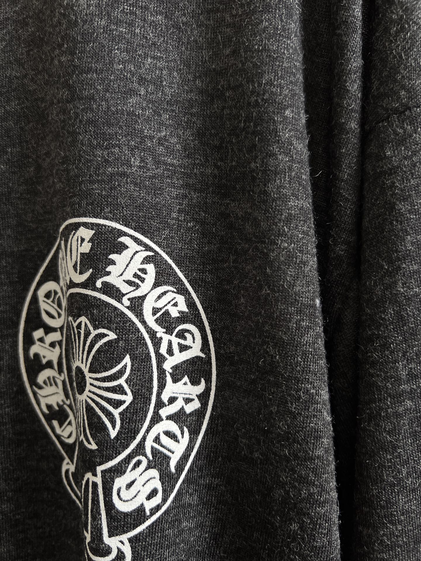 Close-up of circular crest logo on dark heather gray long-sleeve T-shirt