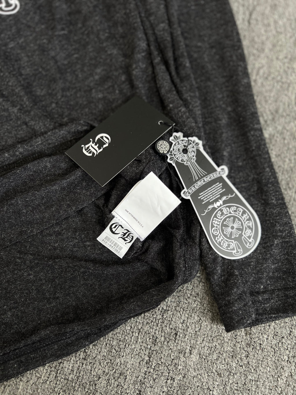 Long-sleeve T-shirt with attached hang tags on dark heather gray fabric