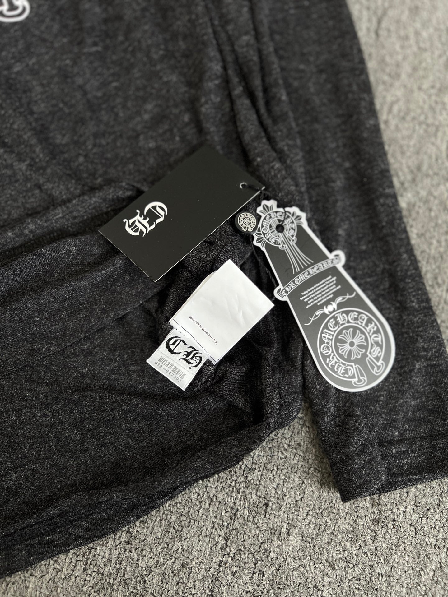 Long-sleeve T-shirt with attached hang tags on dark heather gray fabric