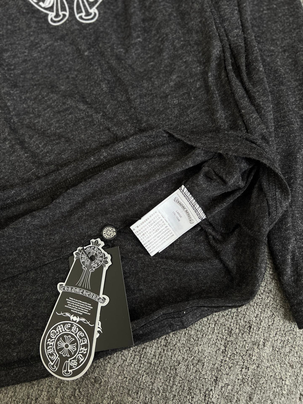 Long-sleeve T-shirt with hang tag labels on dark heather gray fabric fold