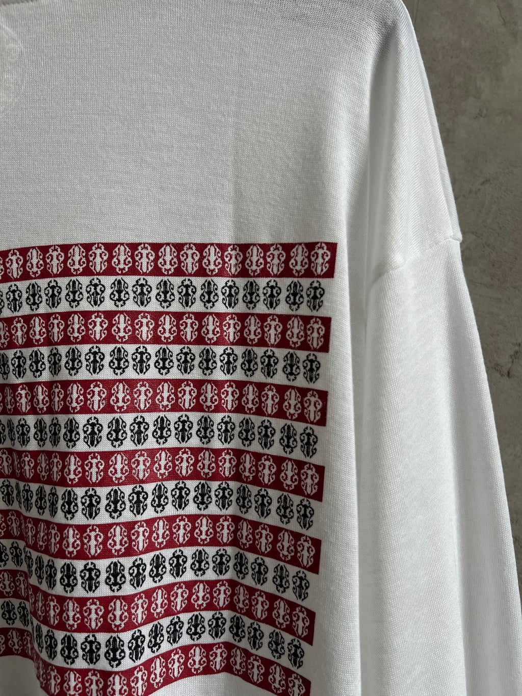 Back of white long-sleeve shirt with horizontal striped graphic band across upper back.