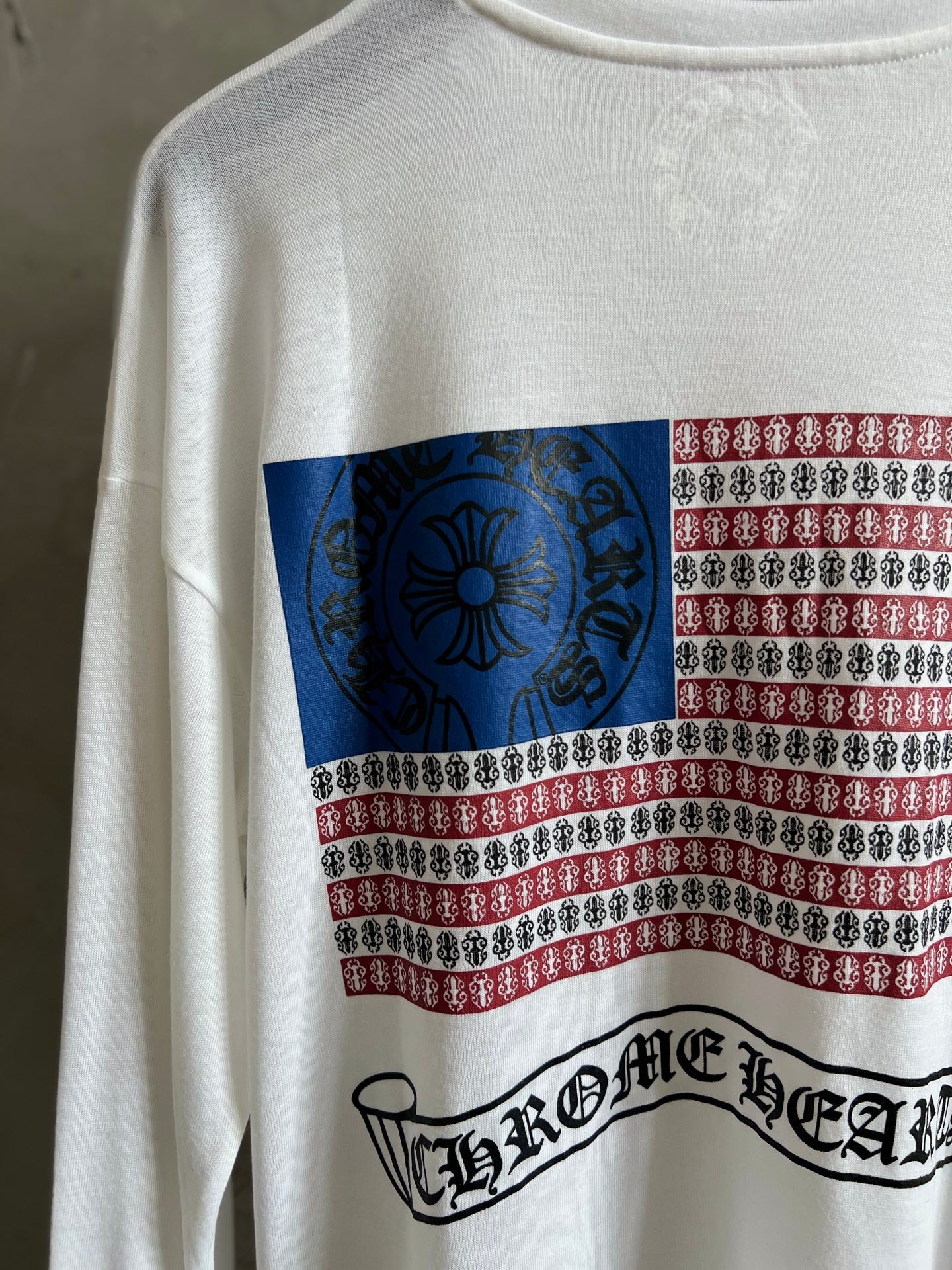 Close-up of front print: blue floral emblem with red, white, and black striped band.