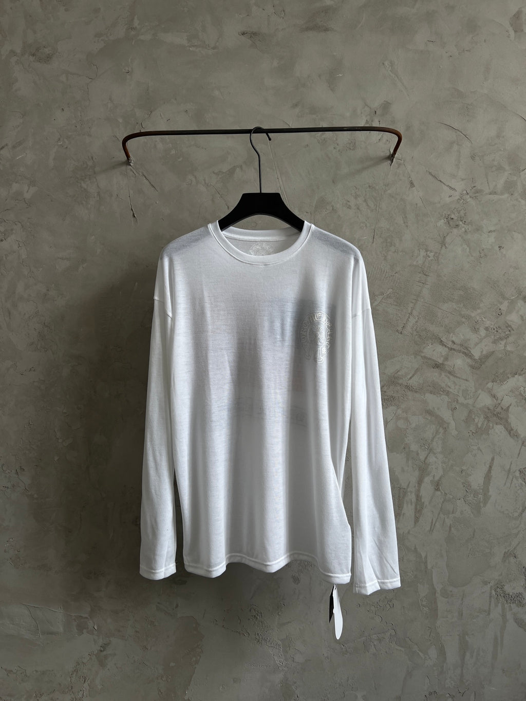 White long-sleeve crewneck shirt with large chest graphic, laid flat on hanger.