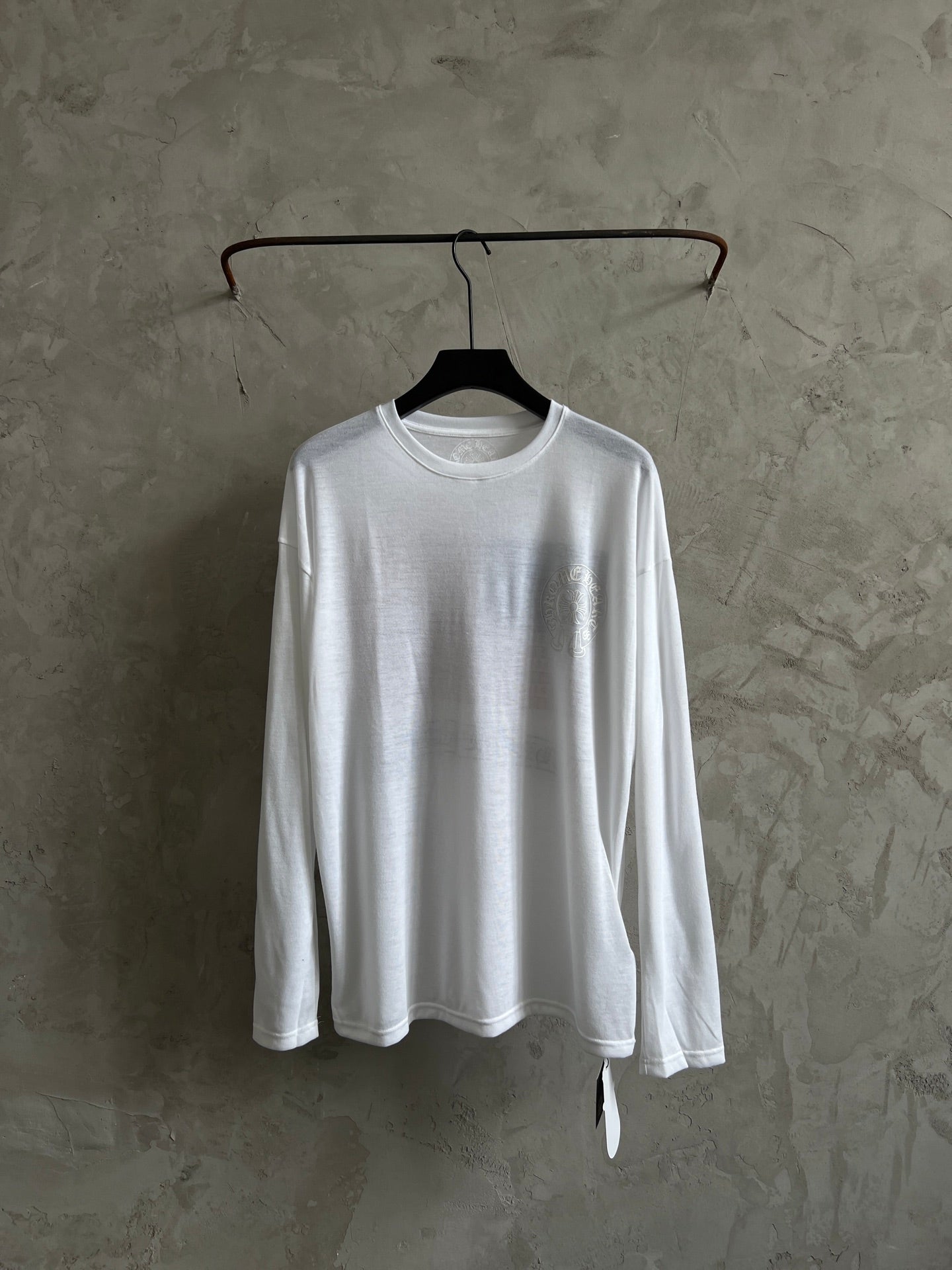 White long-sleeve crewneck shirt with large chest graphic, laid flat on hanger.