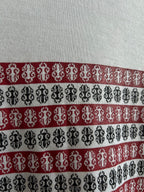 Close-up of horizontal striped graphic in black, red, and white on white shirt.