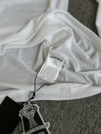 White long-sleeve top with printed hang tag and neckline label