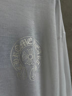Close-up of white shirt with circular crest logo on the left chest area.