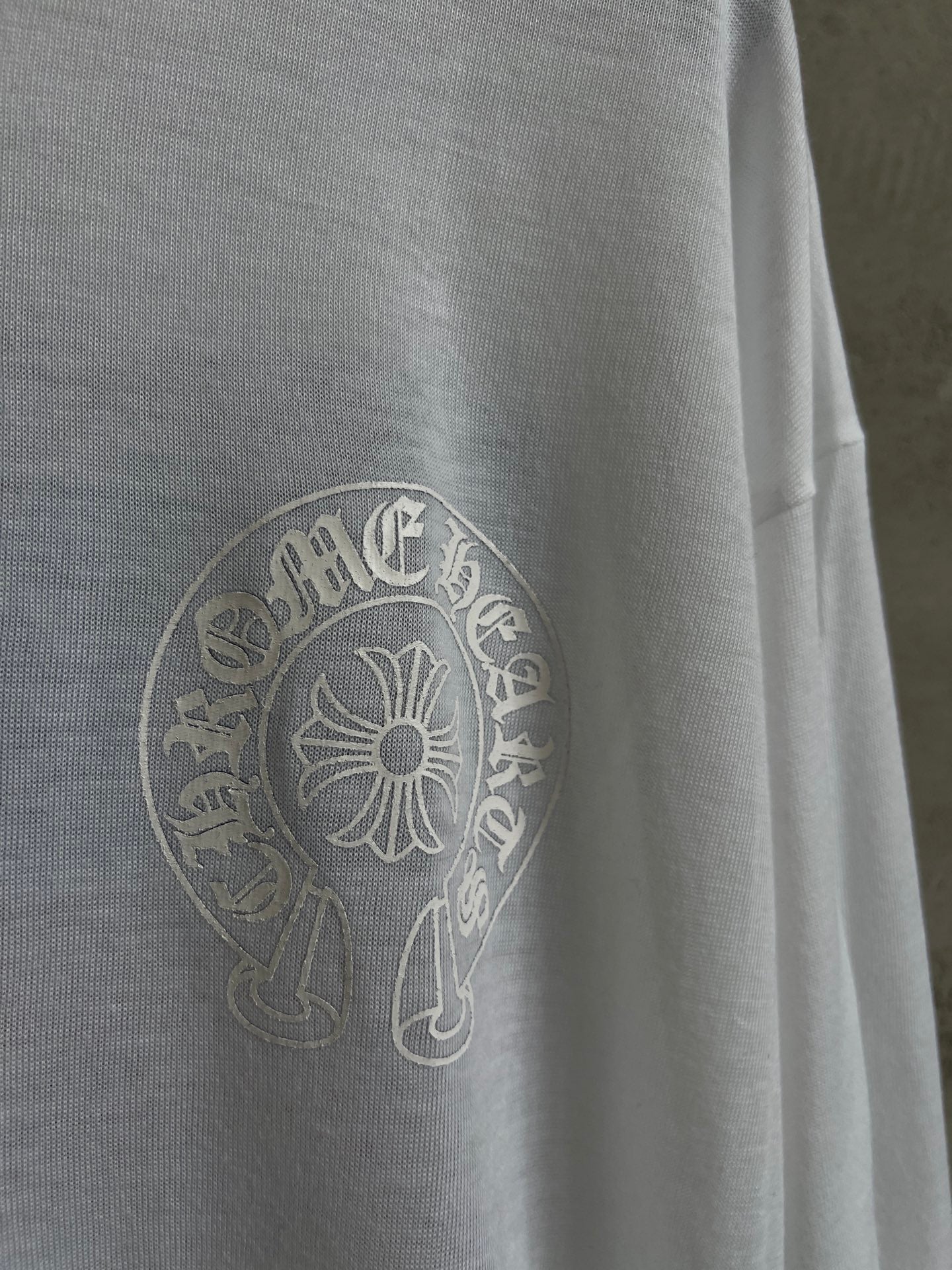 Close-up of white shirt with circular crest logo on the left chest area.