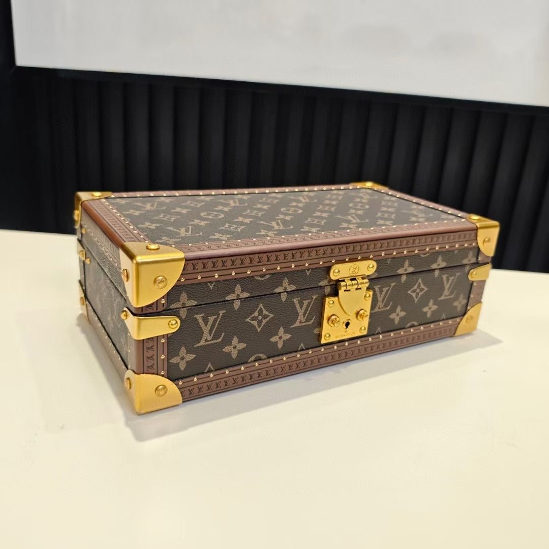 Louis Vuitton monogram trunk bag on tabletop with gold feet and closed lid