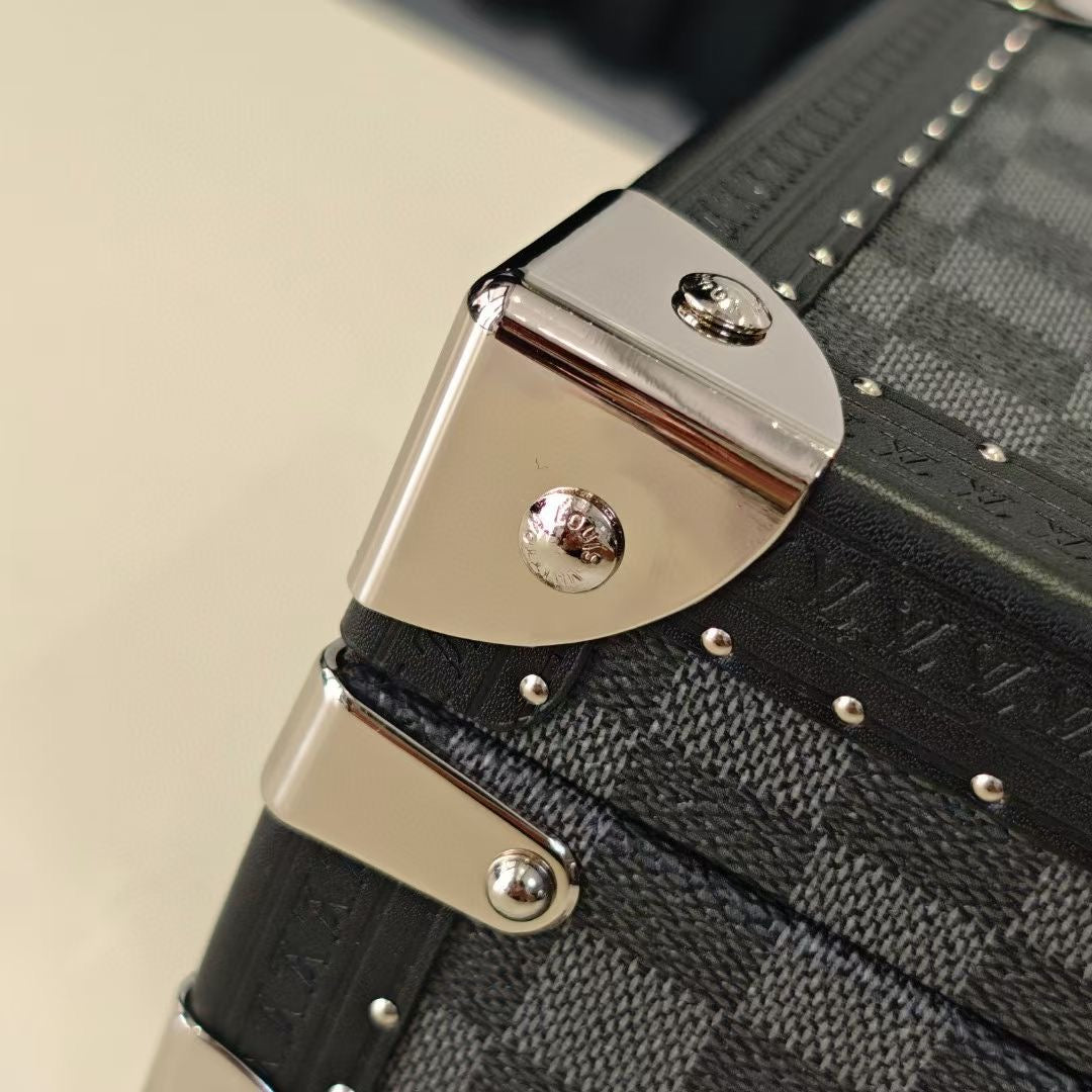 Metal corner clasp on checkered storage case with riveted strap
