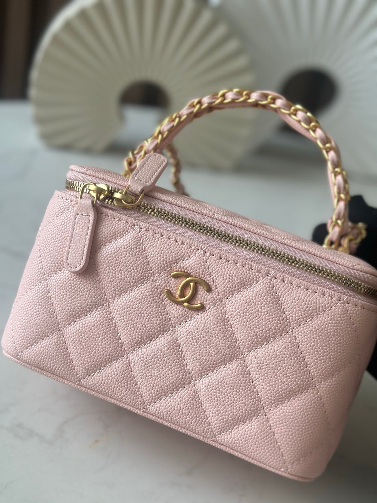Chanel mini bag top view in light pink quilted fabric with gold zipper hardware