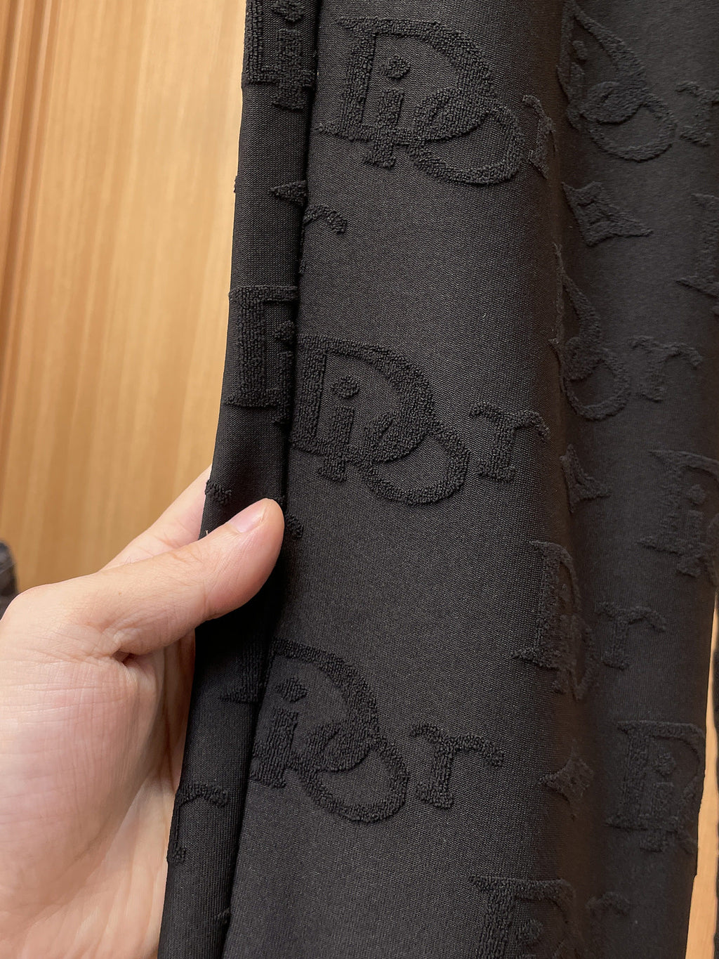 Close-up of black Dior monogram fabric texture on the leg