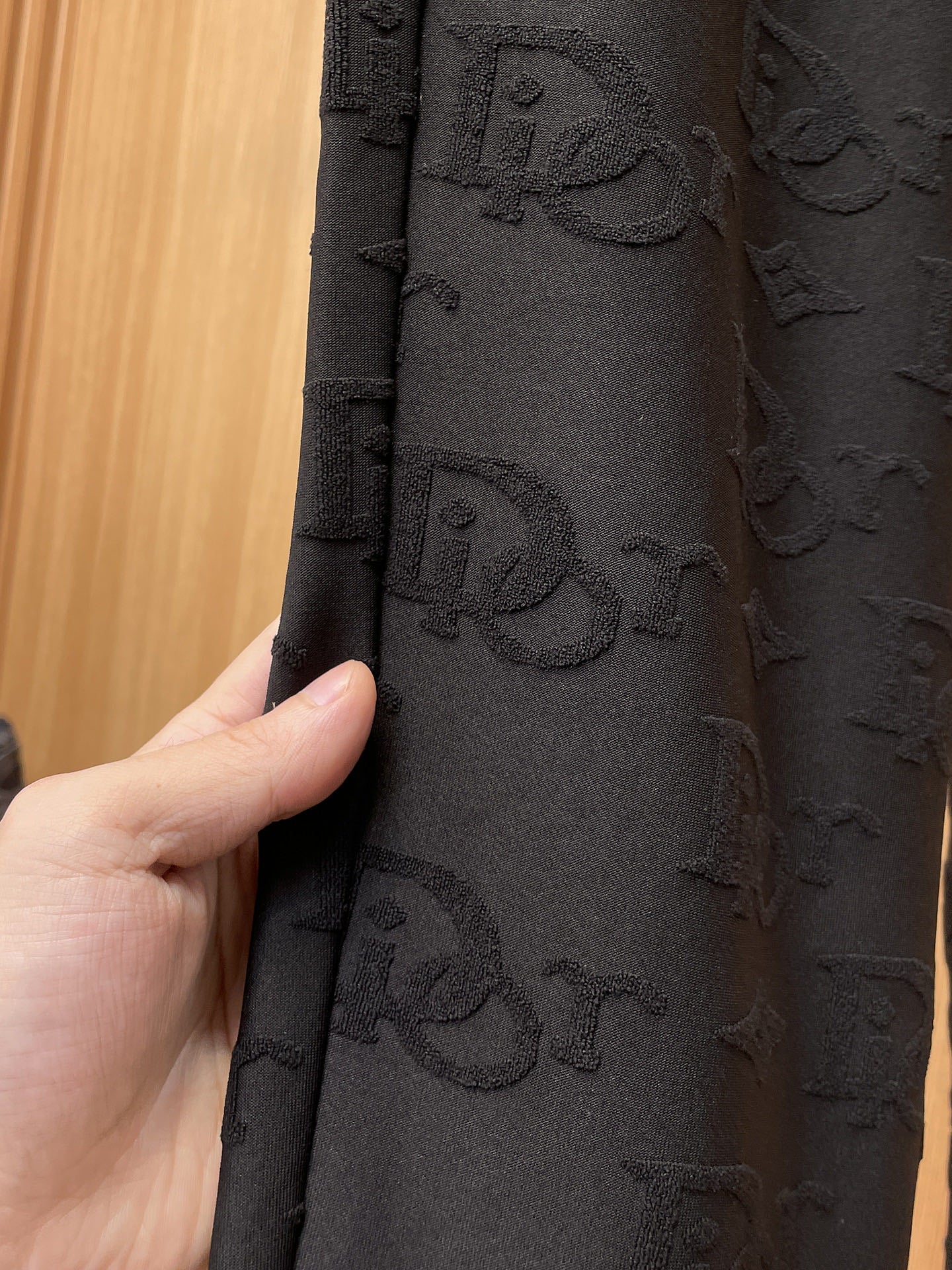Close-up of black Dior monogram fabric texture on the leg