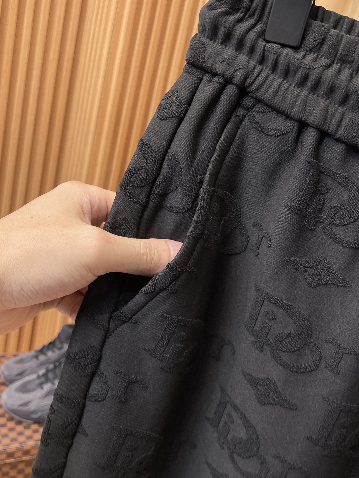 Hand-adjusted view of black elastic waistband on Dior monogram pants
