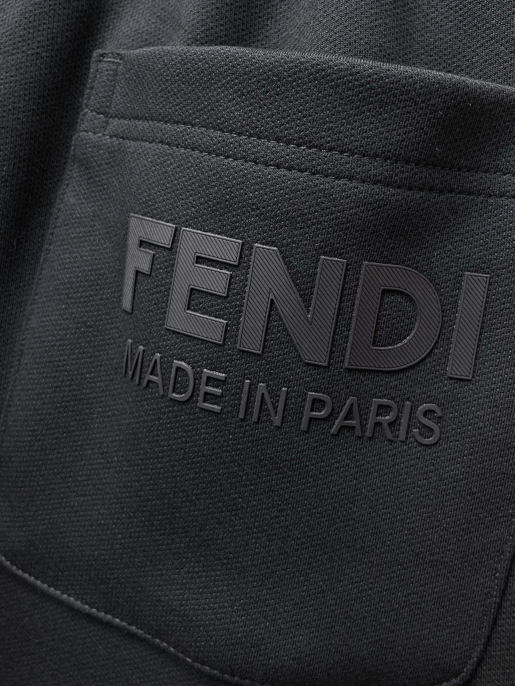 Fendi pants logo patch reading “FENDI” and “MADE IN PARIS” on dark fabric