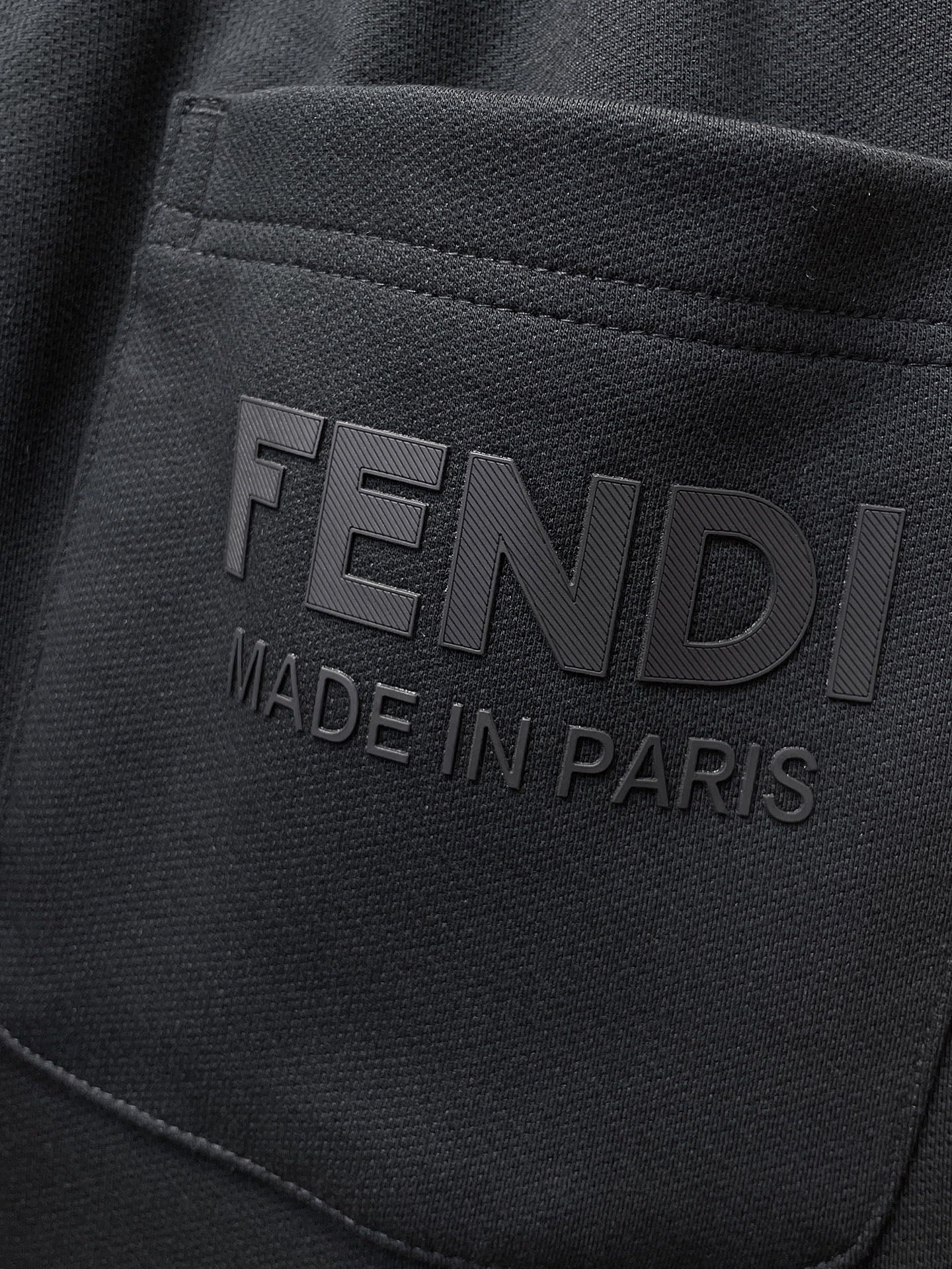 Fendi pants logo patch reading “FENDI” and “MADE IN PARIS” on dark fabric