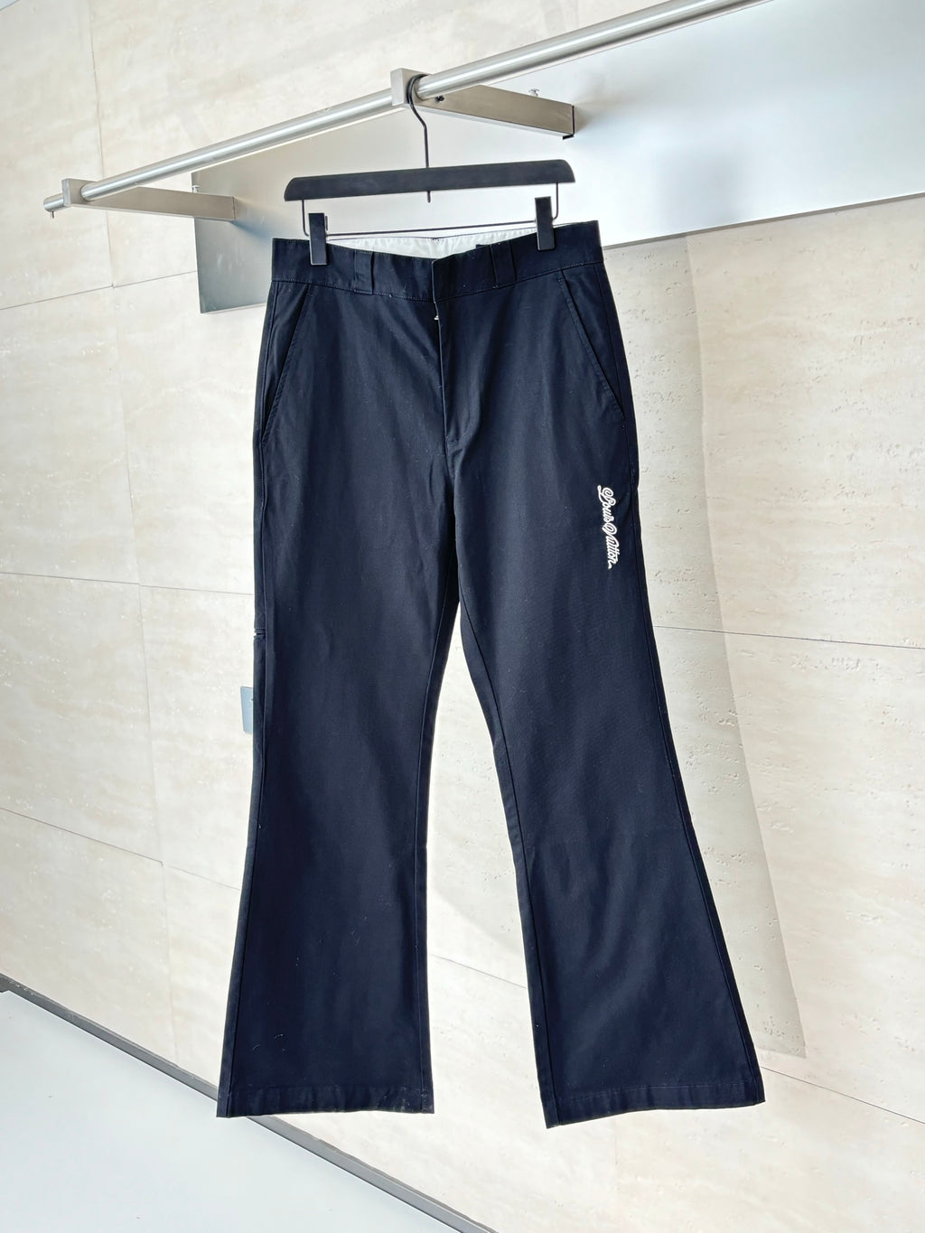 Navy straight-leg pants with belt loops and front zip fly on hanger