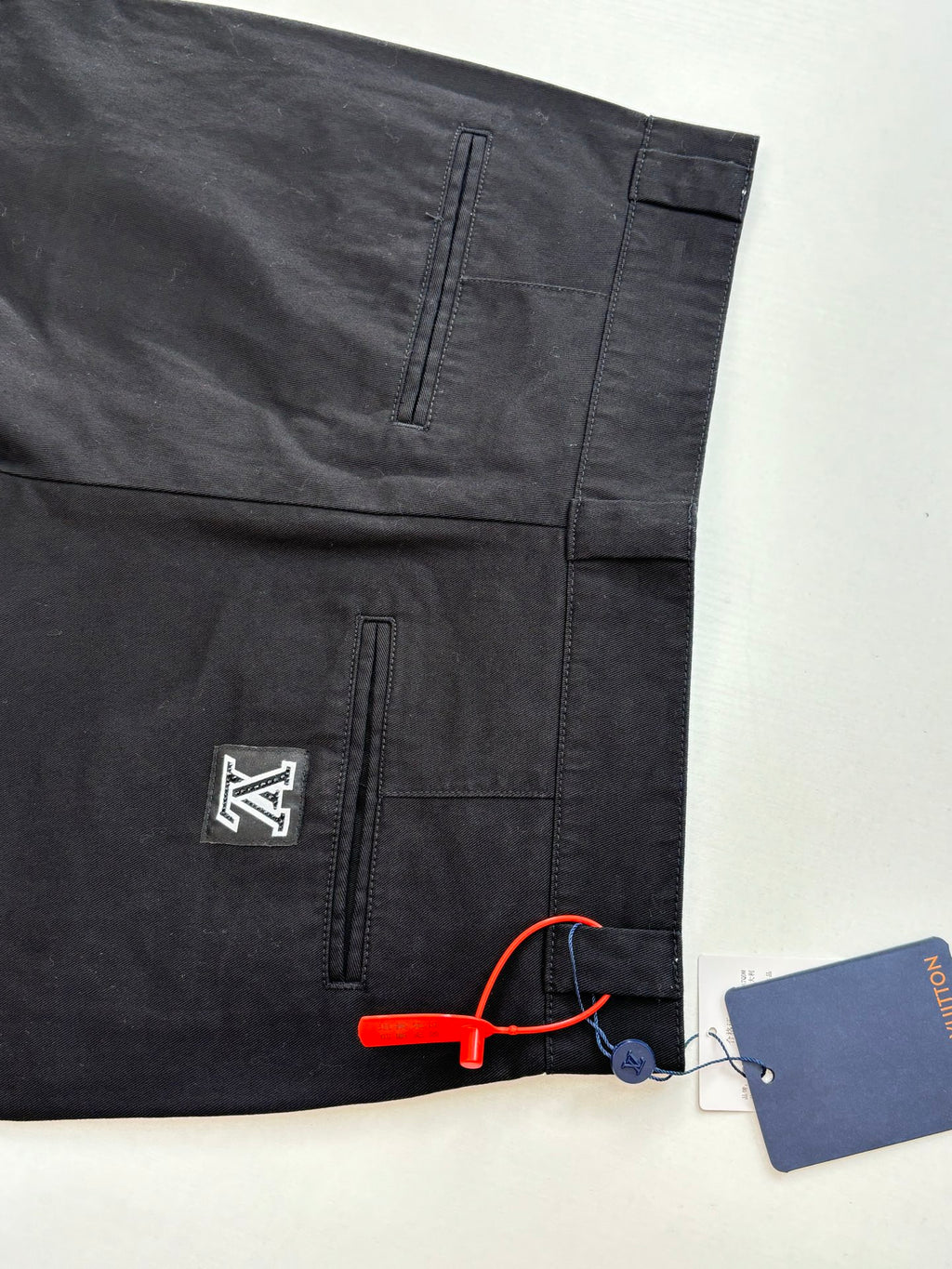 Dark pants with front and back pocket seams, logo patch, and hang tag