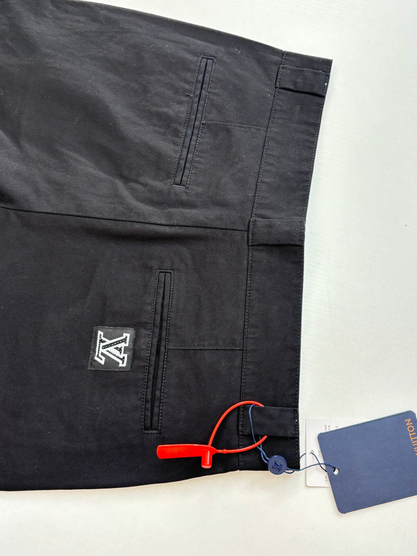 Dark pants with front and back pocket seams, logo patch, and hang tag