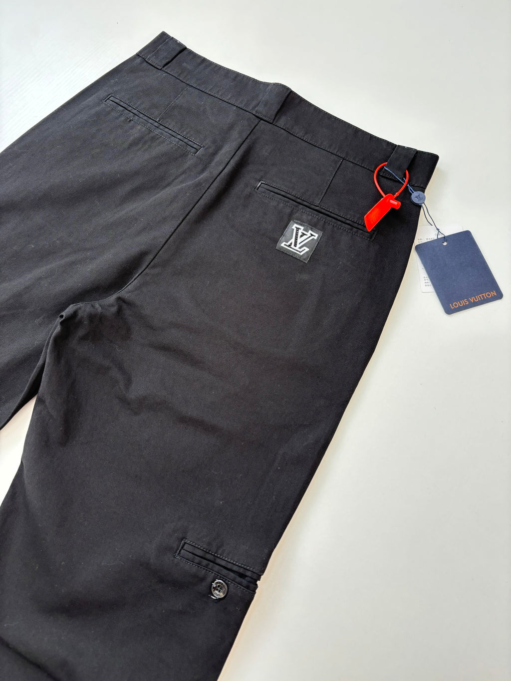 Louis Vuitton dark pants with button closure and side pocket, front view