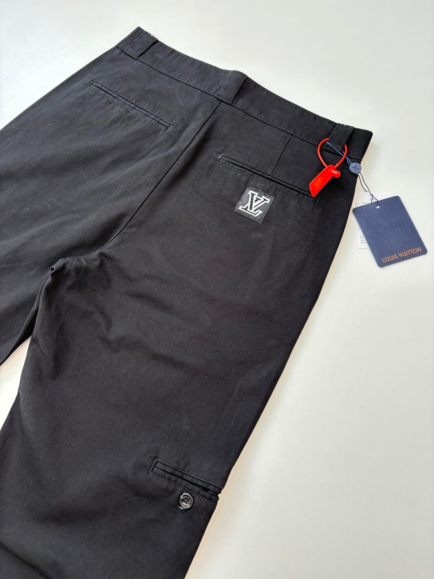 Louis Vuitton dark pants with button closure and side pocket, front view