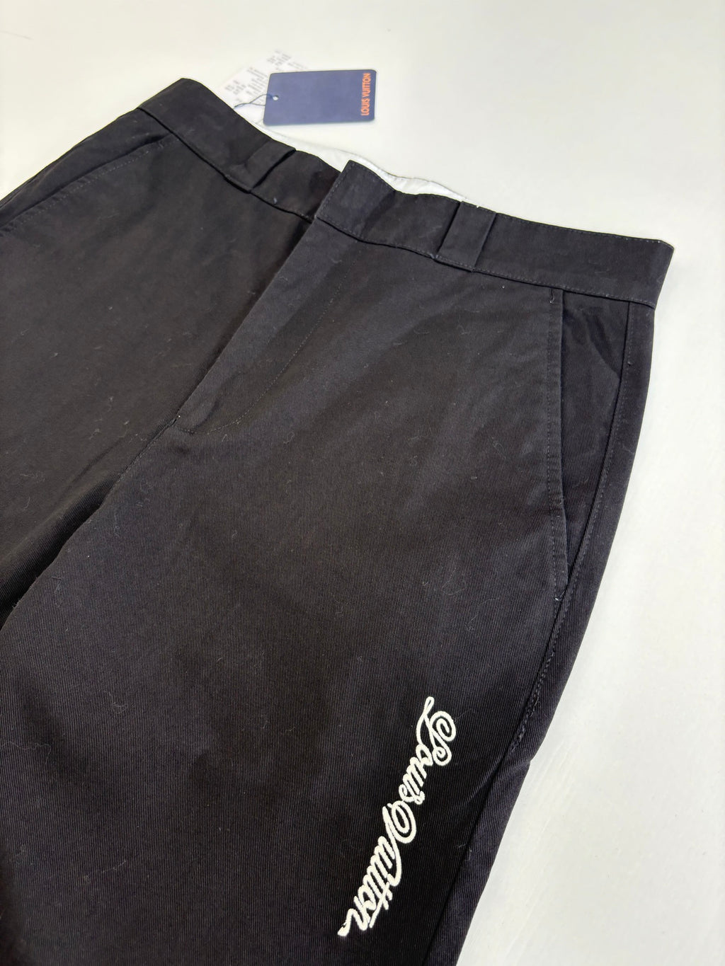 Dark straight-leg pants with embroidered side logo and front crease