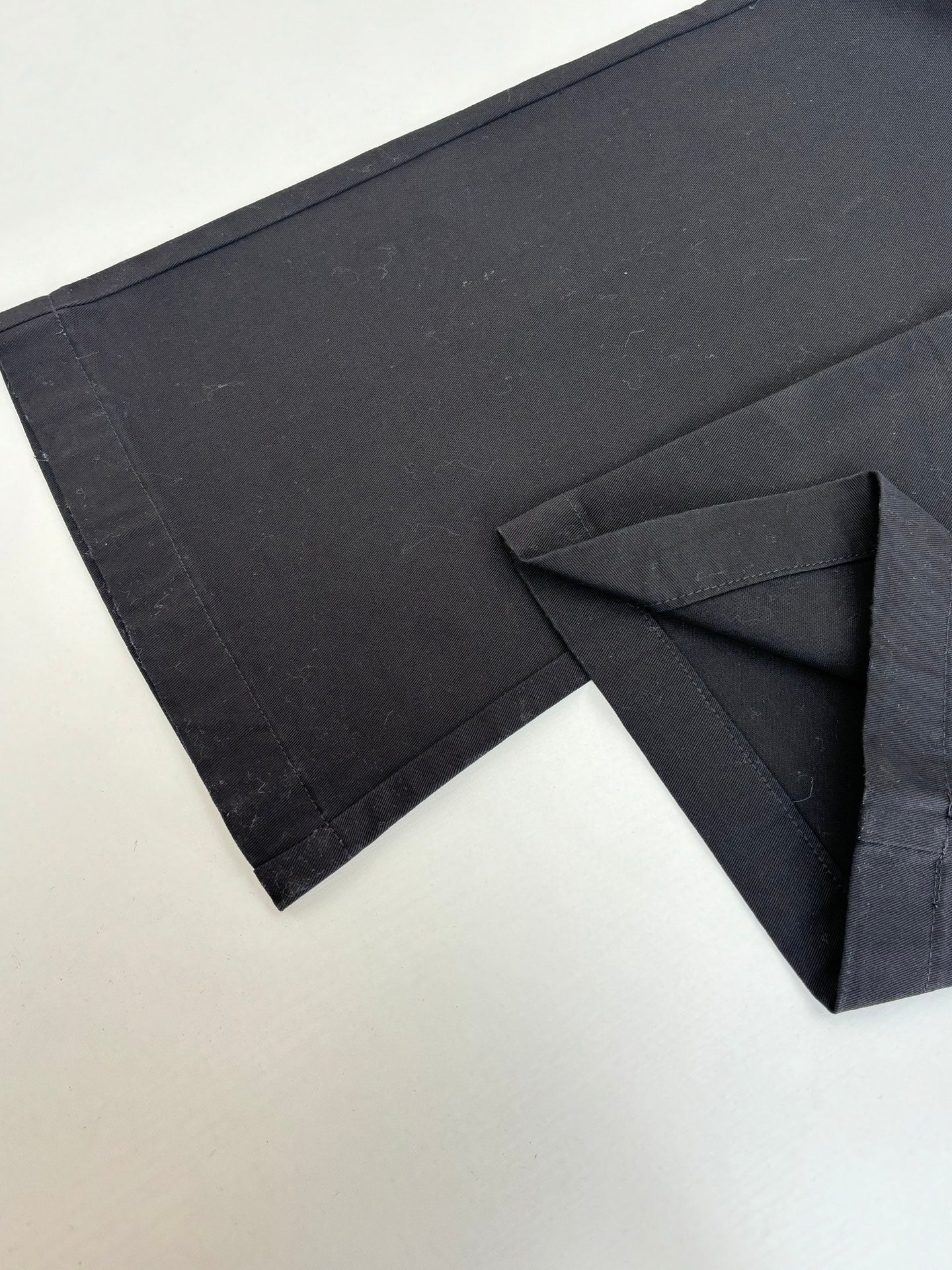 Dark pants with side cargo-style pocket opening and stitched panel detail