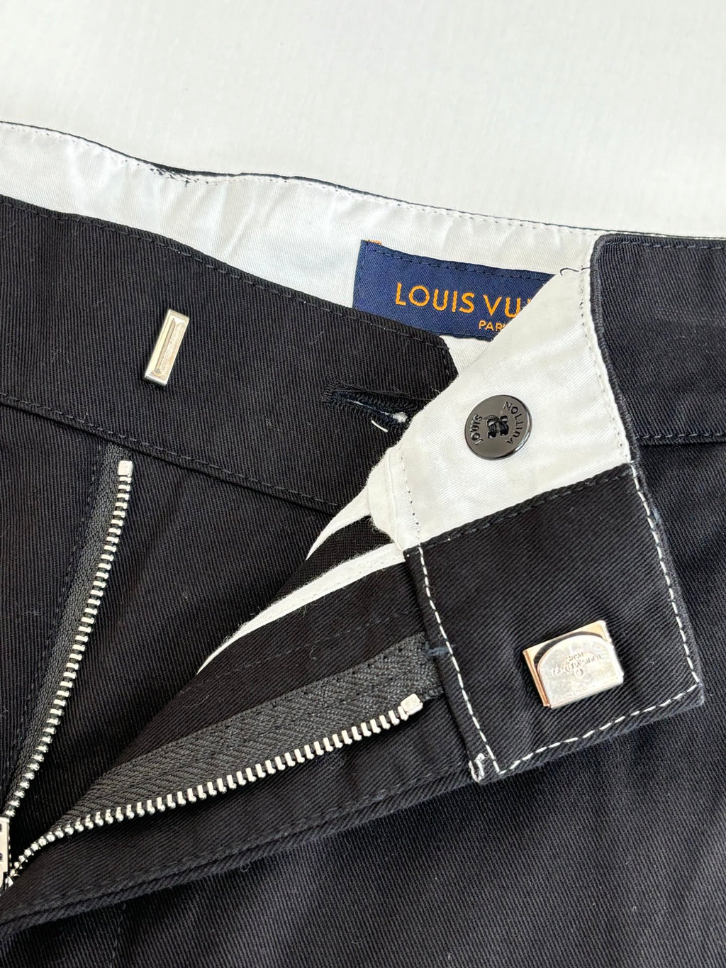 Dark pants waist with zip fly, button closure, and interior tag labels