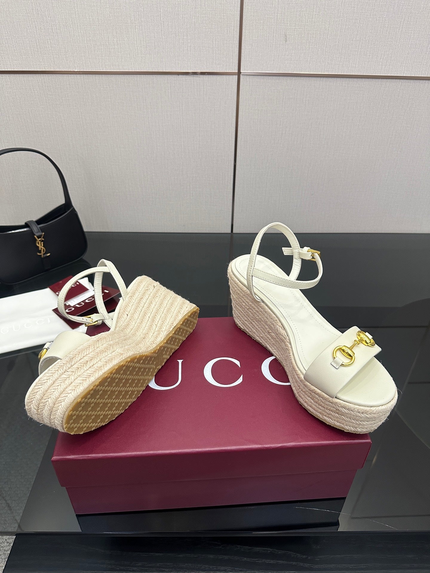 Gucci white wedge sandals with gold buckle; one shows red-trim strap detail.