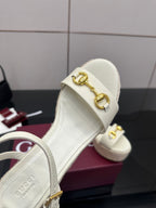 Gucci white leather wedge sandal closeup with gold buckle and slingback strap.
