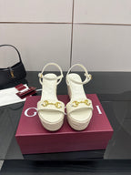 Gucci white platform wedge sandals with gold buckle detail and ankle straps.