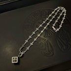 Silver-tone cross-link chain necklace with square pendant charm on dark box